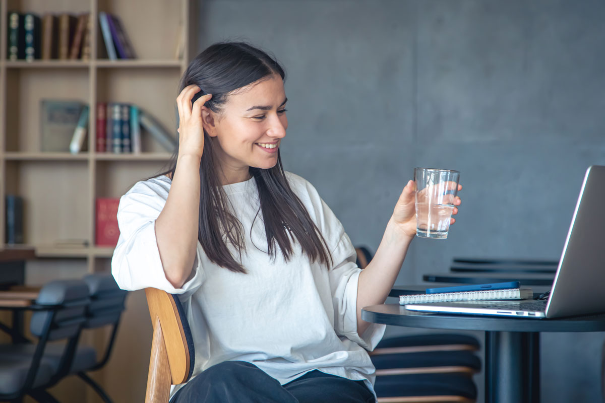 young-woman-with-a-glass-of-water-in-front-of-a-la-2023-11-27-04-50-08-utc Woman drinking a glass of clear water in a bright, modern kitchen, smiling and enjoying the refreshing taste.